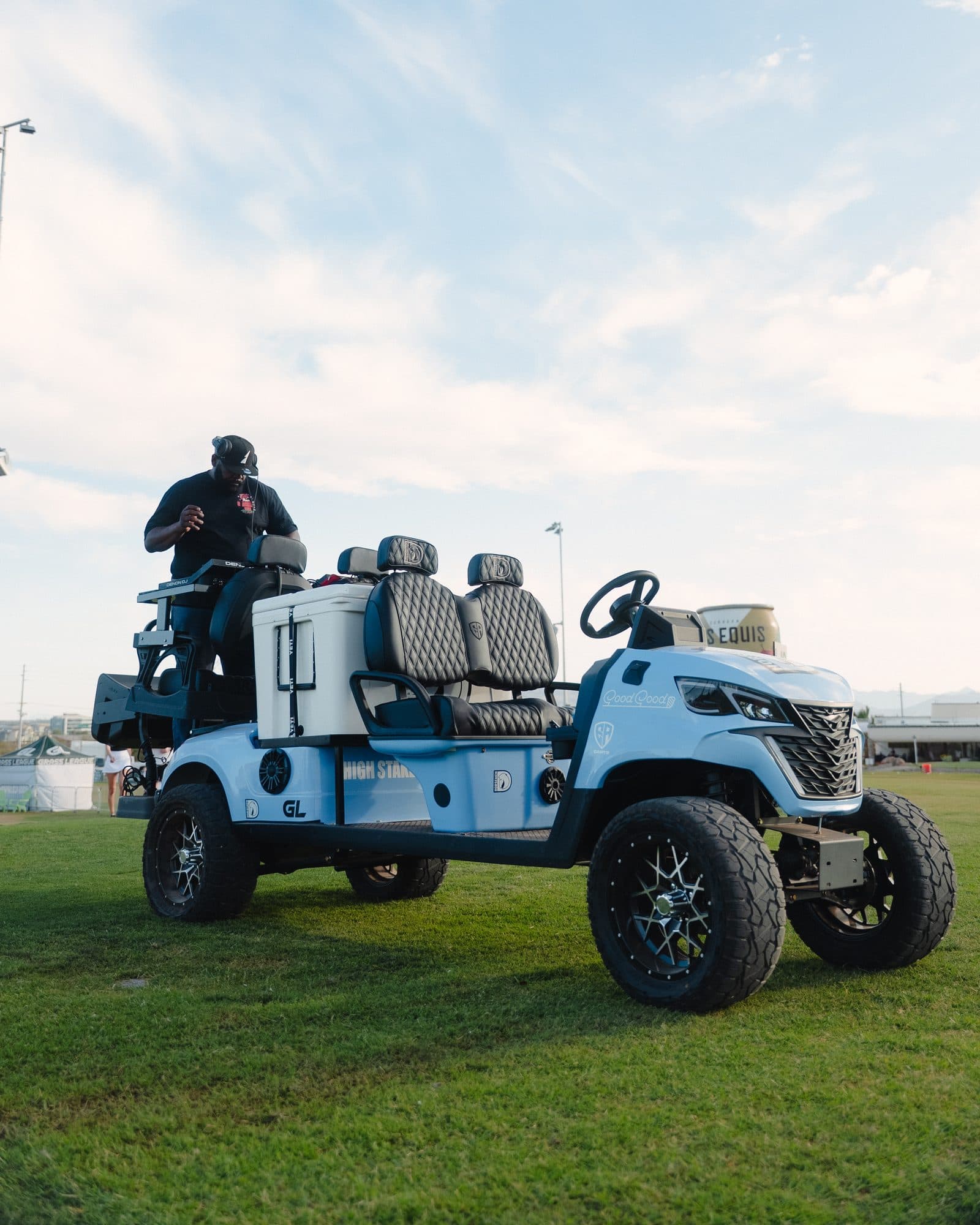 Light blue Good Good custom EA Carts golf cart with black quilted seats and a rear cooler on grass