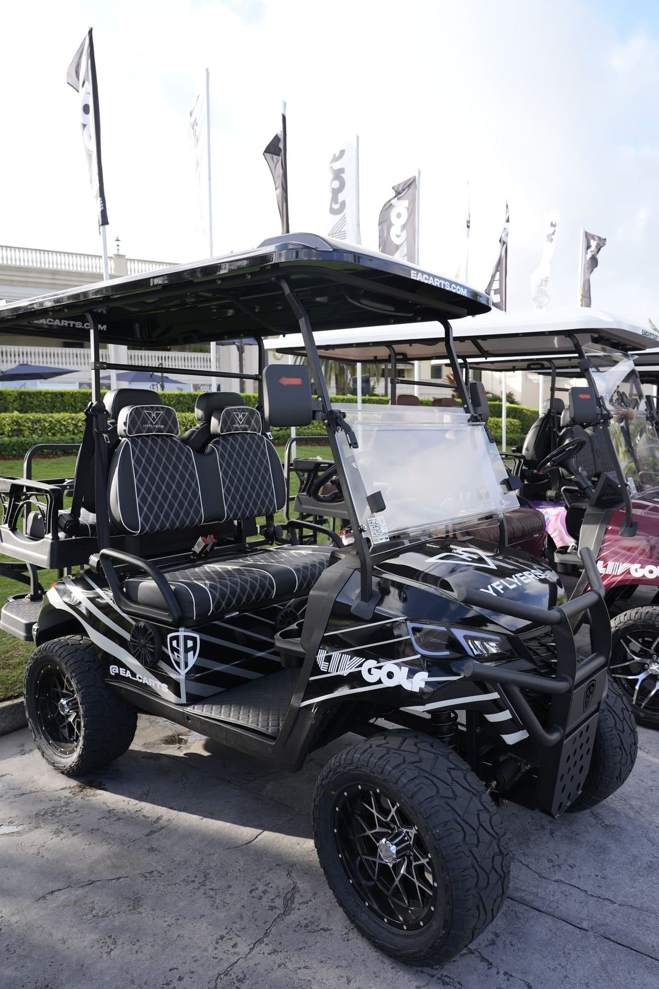 EA Carts golf cart in a black and white LIV Golf custom wrap with white-stitched black seats, team flags behind