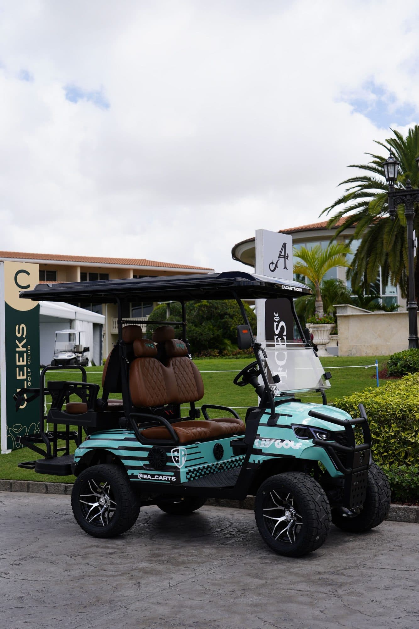 EA Carts golf cart in a teal LIV Golf custom wrap with brown quilted seats outside a clubhouse