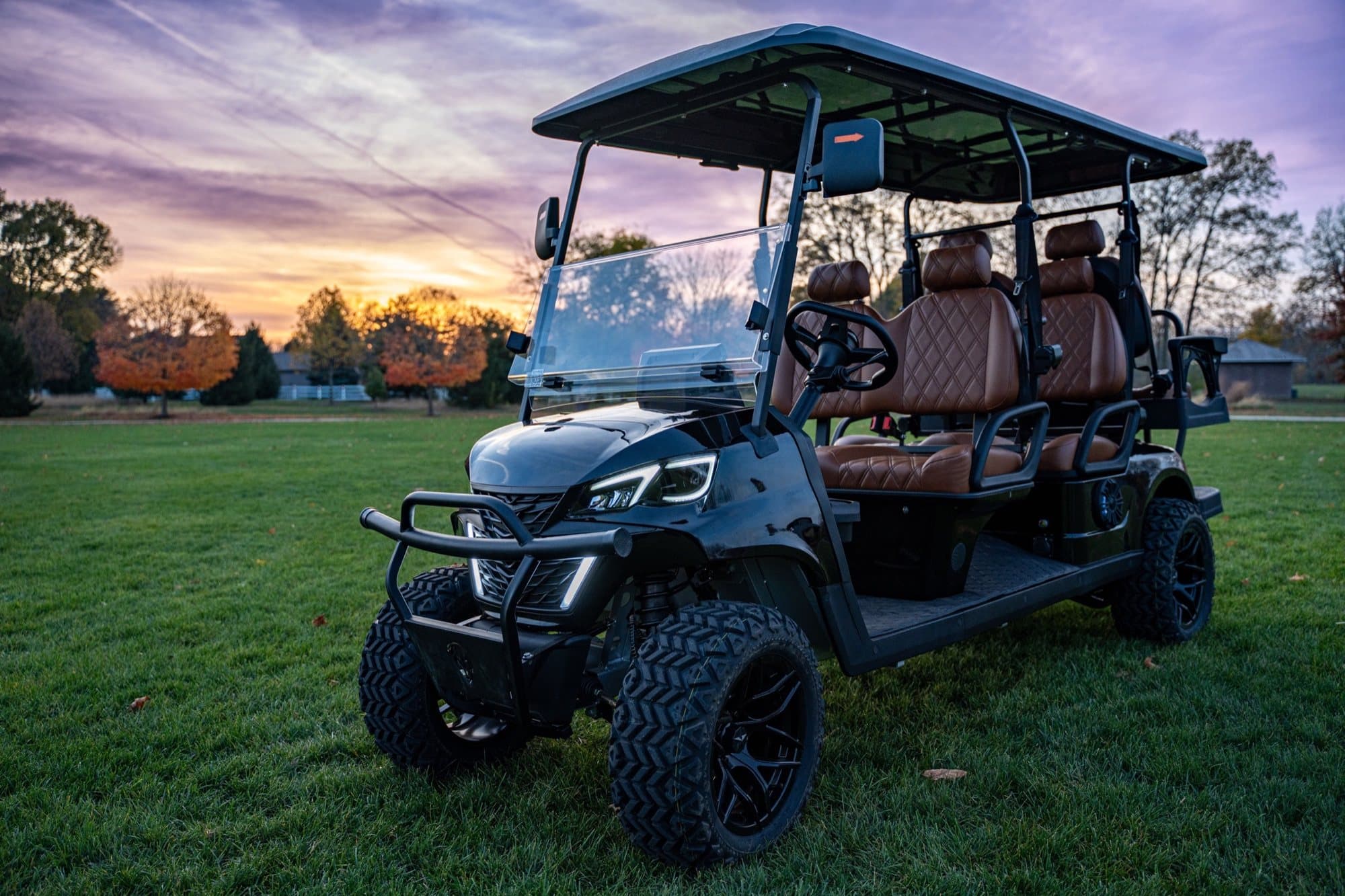 EA6R+ 72V six-seat lithium electric golf cart in black with brown seats at sunset