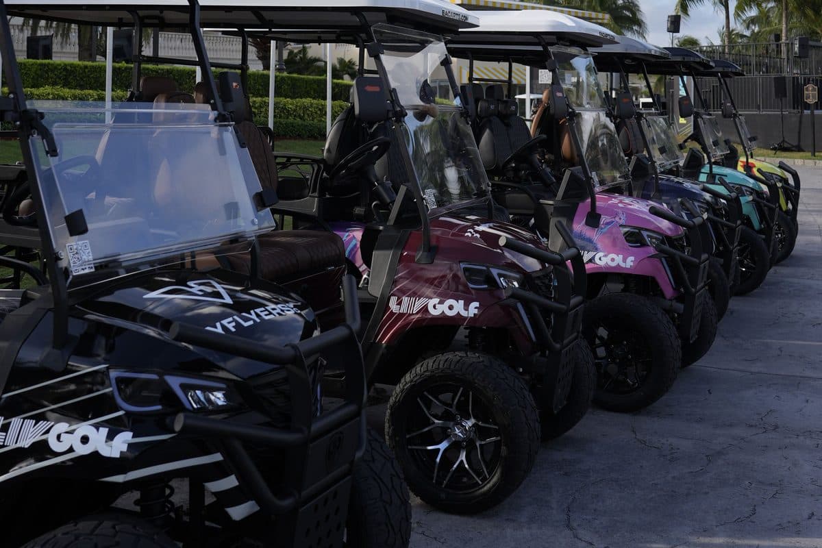 Row of EA Carts golf carts in LIV Golf team wraps, black, maroon, pink and teal, parked along a walkway