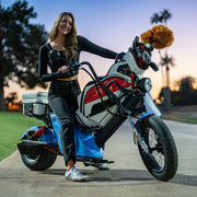 Woman sitting on a custom EA Golf Cart with a fluffy object on the handlebar, outdoors.